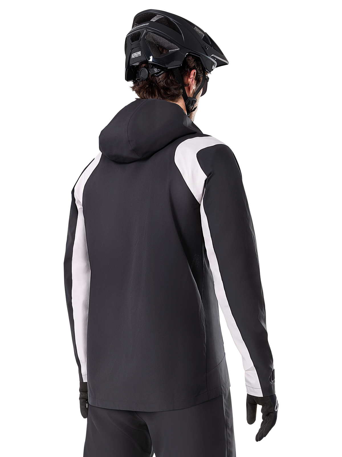 Alpinestars A-Dura Regenjas, mountainbike regenjas, zwart met witte mouwpanelen, achteraanzicht van rijder met een zwarte MTB-helm en handschoenen, technische 2,5-laags waterdichte constructie, mountainbike kleding