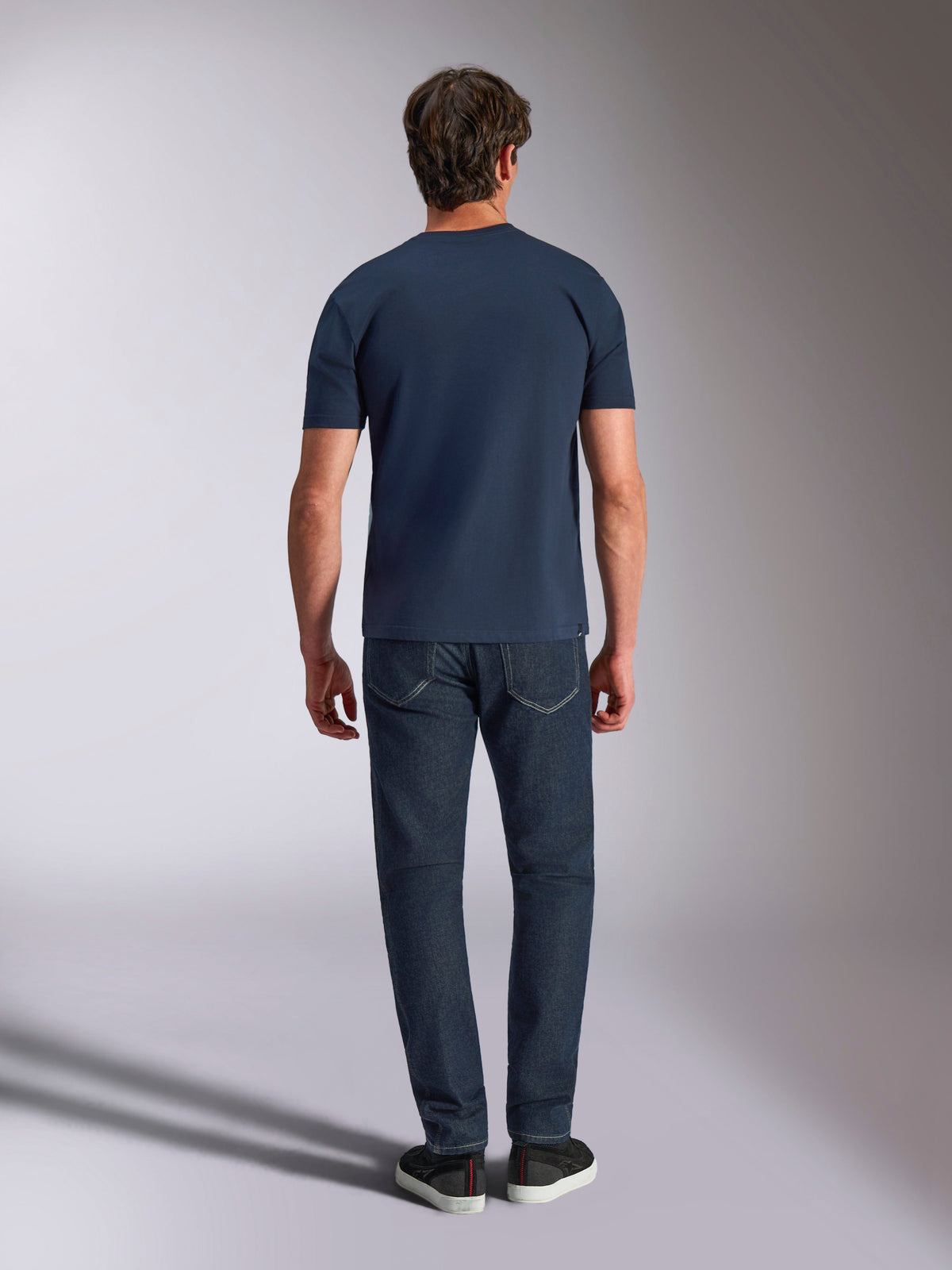 Alpinestars Ageless Shadow CSF Tee, T-shirt met korte mouwen, navy, achteraanzicht van een model dat het shirt draagt met een donkere jeans en zwarte sneakers, casual motorsport streetwear.