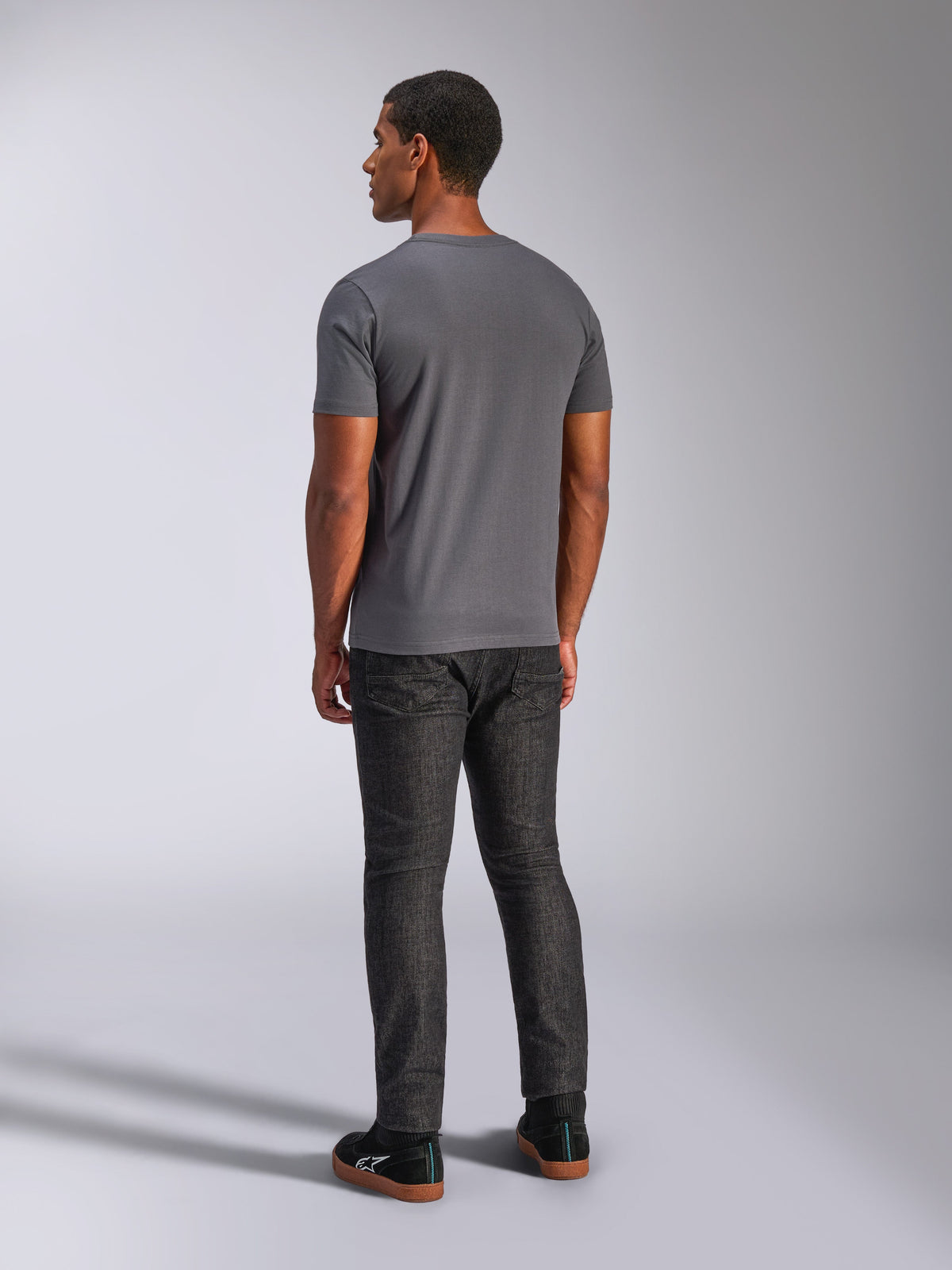 Alpinestars Always 2.0 CSF Tee, T-shirt met korte mouwen, antracietgrijs, achteraanzicht op model, gecombineerd met een donkere denim broek en zwarte sneakers, casual streetwear geïnspireerd op de motorsport