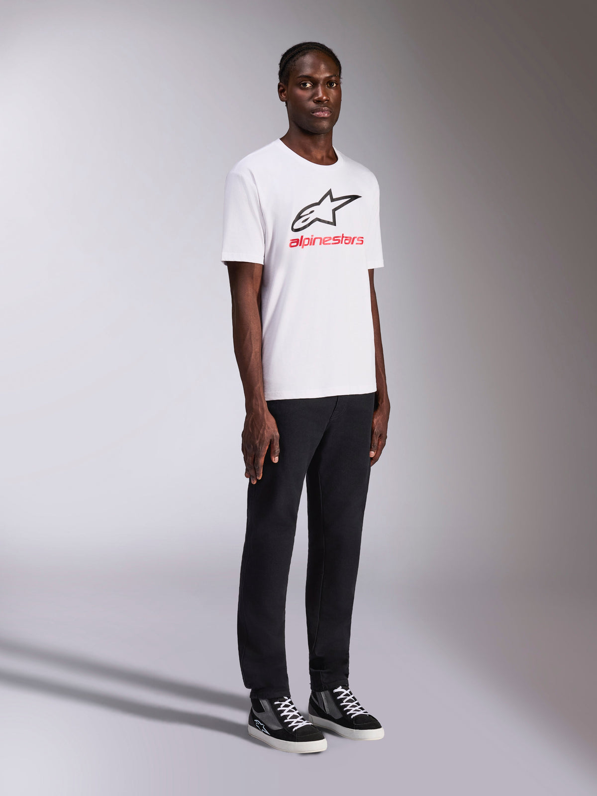 Alpinestars Always 2.0 CSF Tee, T-shirt met korte mouwen, wit, zwart Alpinestars-logo en rode belettering op de borst, gedragen door model met zwarte broek en sneakers, casual motorsport streetwear