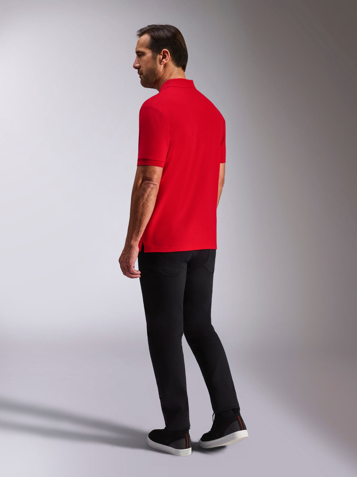 Alpinestars Endeavor Classic Polo, piqué poloshirt met korte mouwen, rood, achter- en zijaanzicht, voorzien van een geribde kraag en manchetten, gedragen met een zwarte broek en schoenen, casual motorsport-geïnspireerde streetwear