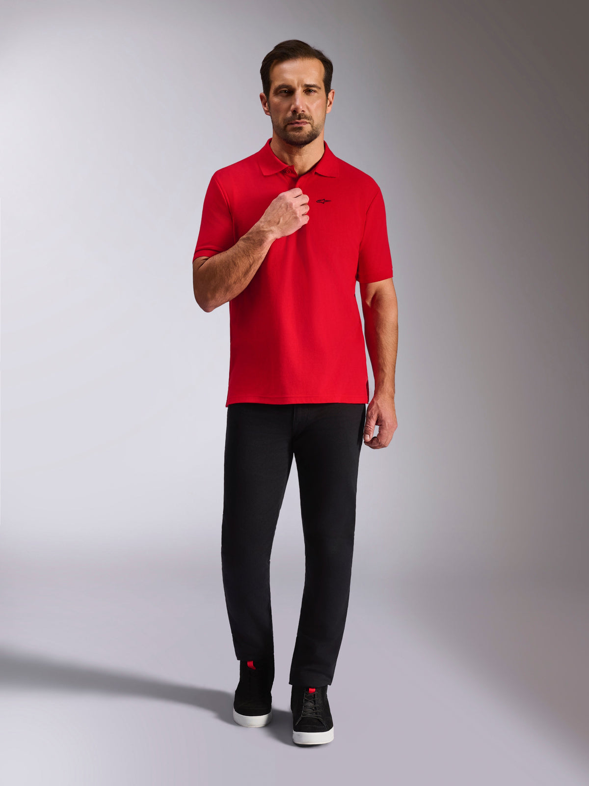 Alpinestars Endeavor Classic Polo, rood piqué poloshirt, korte mouwen met zwart Astars-logo, geribde kraag en manchetten, gedragen met zwarte broek en sneakers, casual op motorsport geïnspireerde streetwear