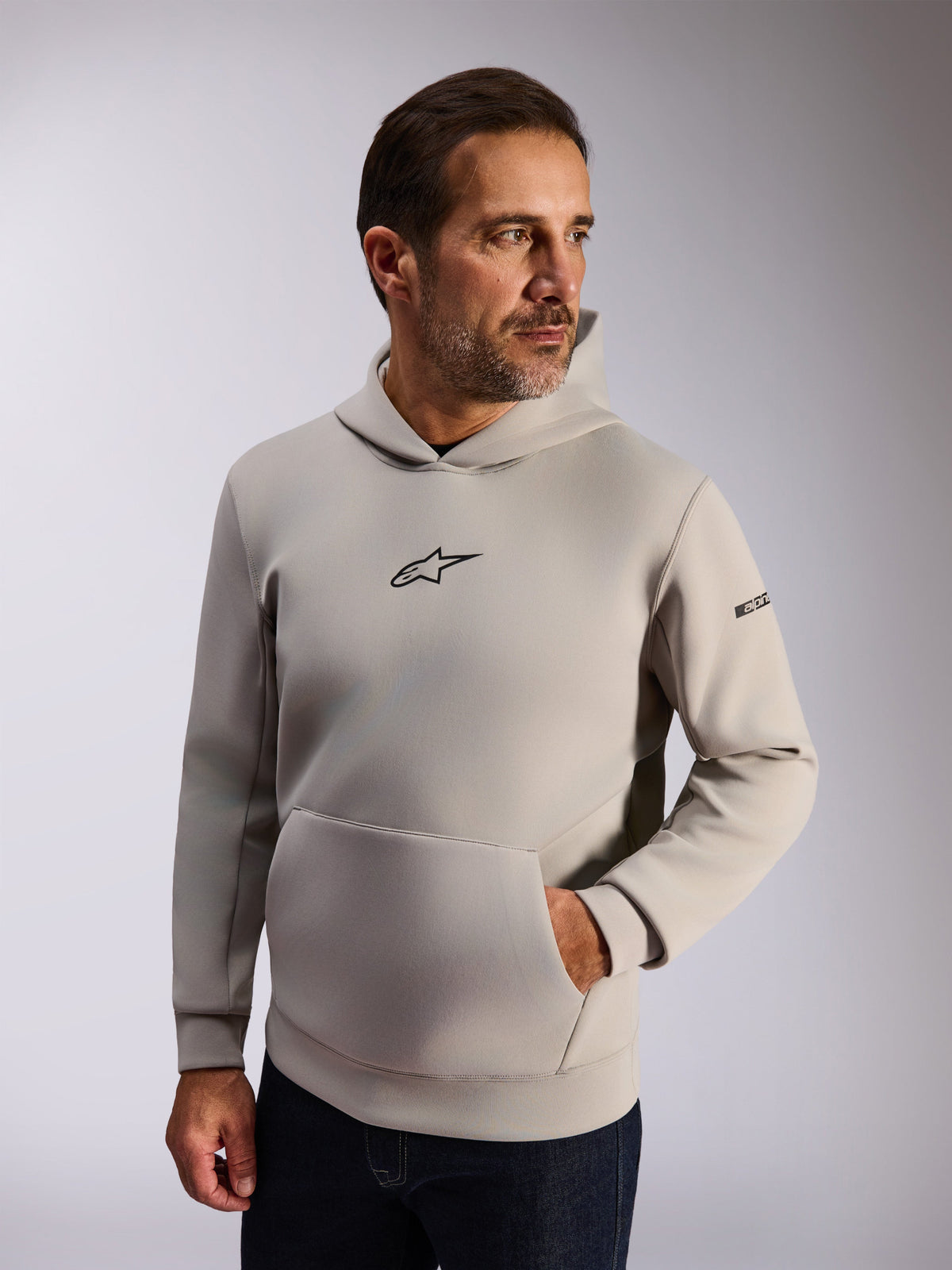 Alpinestars Insight Hoodie, casual lifestyle streetwear, Cement gray fleece, front black Astars logo, kangaroo pocket, sleeve wordmark, mesh-lined hood, modern motorsport-inspired apparel
