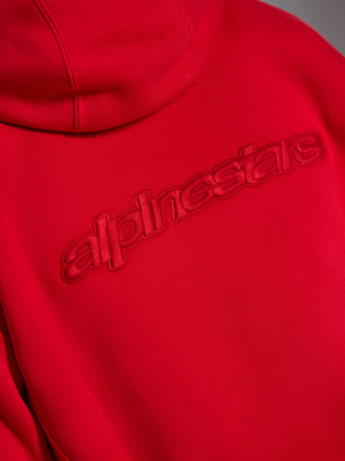 Alpinestars Emergent Oversized Hoodie, rood, close-up van de achterkant met ton-sur-ton 3D-geborduurd Alpinestars-woordlogo, verhoogde monochrome branding op fleece stof