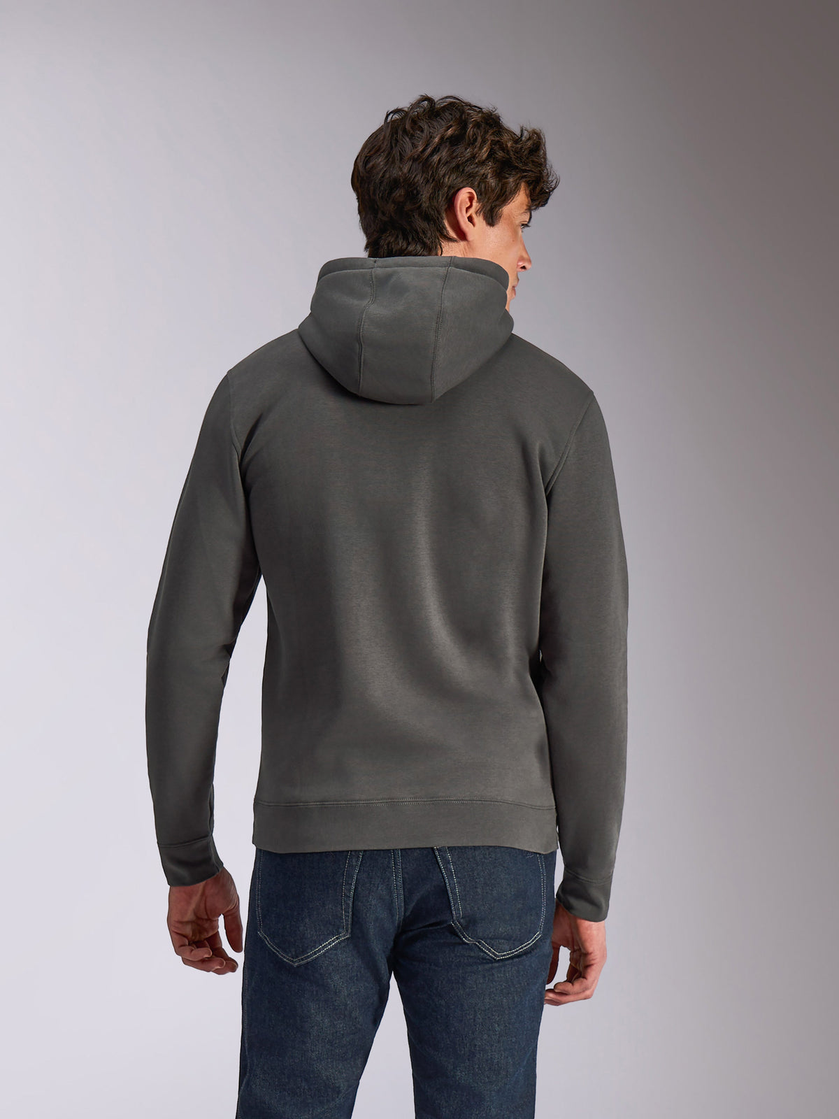 Alpinestars Ellipsoid Hoodie, Gunmetal grijs, casual sportkleding, achteraanzicht van een man die een fleece pullover met capuchon draagt, geribde zoom en manchetten, gecombineerd met een blauwe jeans