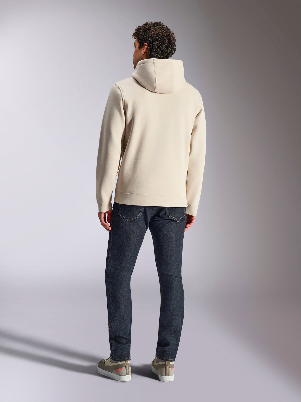 Alpinestars Pulse Hoodie, Off White, achteraanzicht van een man die een casual pullover fleece hoodie draagt met een donkere jeans en sneakers, modern sportkledingontwerp