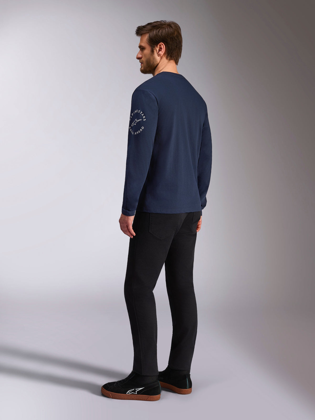 Alpinestars Mandatory CSF T-shirt met lange mouwen, navy, wit cirkelvormig logo op de mouw, achteraanzicht, gedragen met zwarte broek en zwarte sneakers, casual motorsport streetwear
