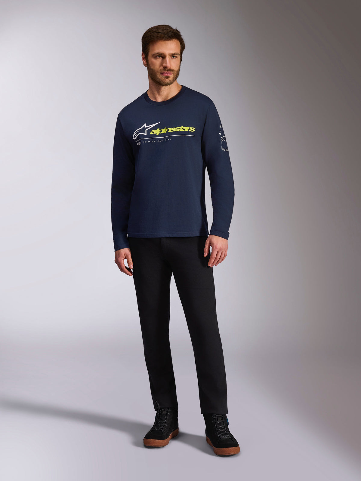 Alpinestars Mandatory CSF Tee, T-shirt met lange mouwen, donkerblauw, wit Astars-logo met neongeel woordlogo, gedragen door een model met een zwarte broek en zwarte sneakers, casual motorsport streetwear