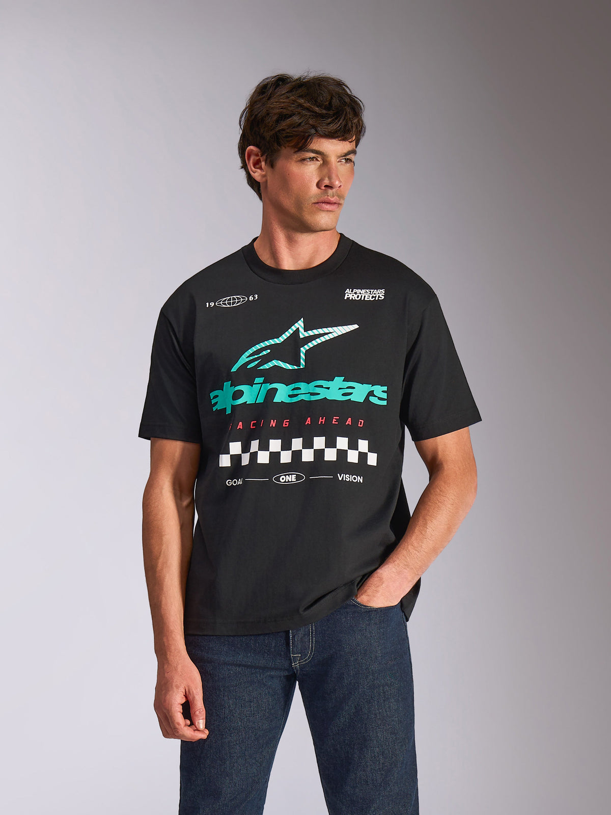 Alpinestars Aplomb Oversized CSF Tee, Short Sleeve T-Shirt, Black, featuring a large teal and white Astars combo logo with checkered graphic, worn by male model with dark blue jeans, casual motorsport streetwear