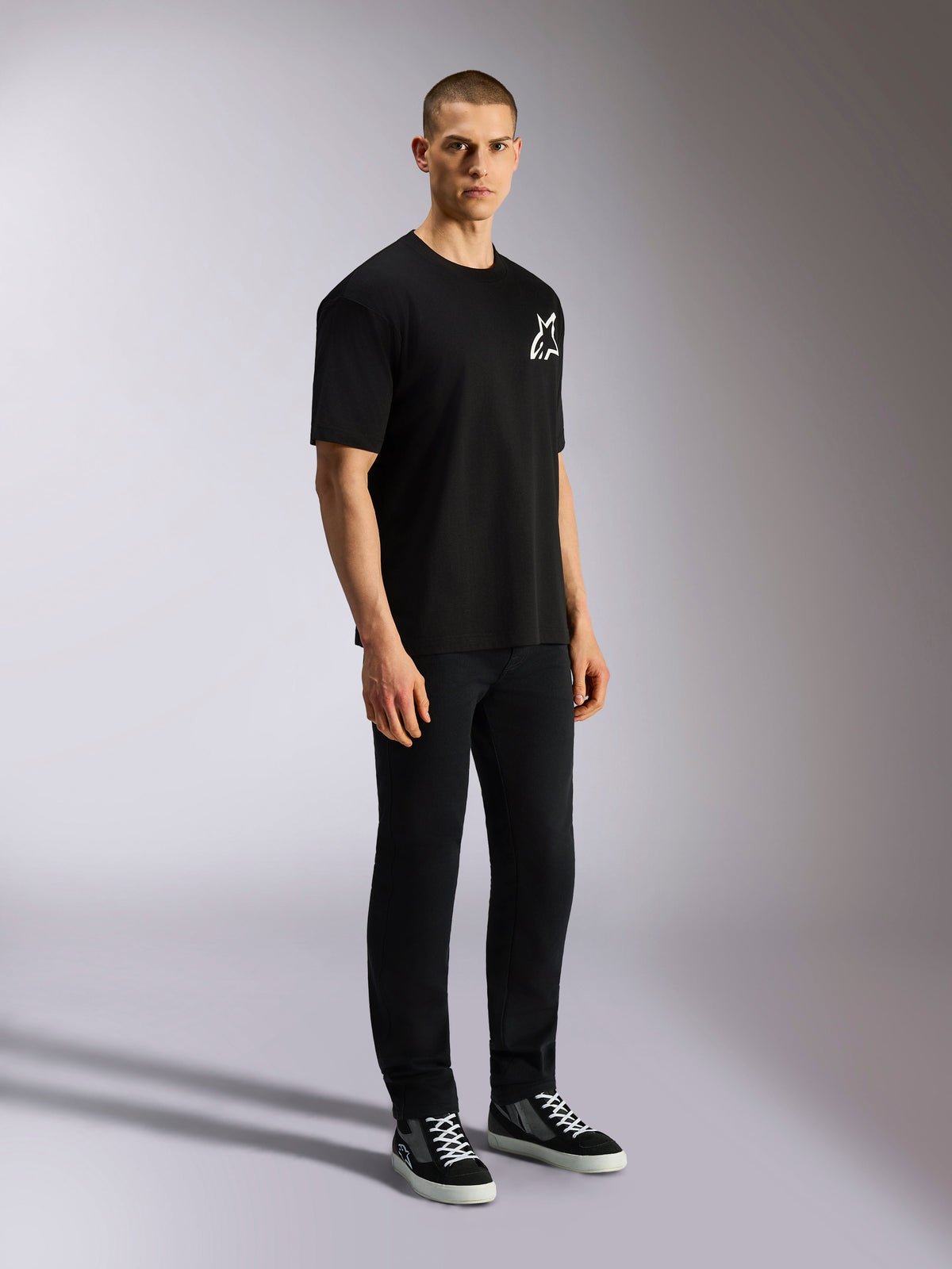 Alpinestars One Oversized CSF Tee, T-shirt met korte mouwen, zwart, wit Astars-logo op de borst, oversized pasvorm, gedragen door een mannelijk model met een zwarte broek en sneakers, casual op motorsport geïnspireerde streetwear