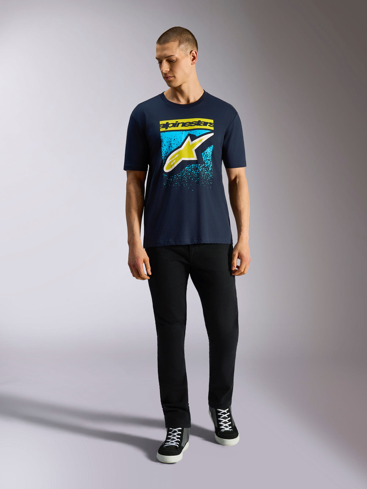 Alpinestars Noka CSF Tee, Short Sleeve T-Shirt, Navy Blue, Front Astars Logo with Yellow and Light Blue MX Gradation, worn by a model with black pants, Casual Motorsport Streetwear