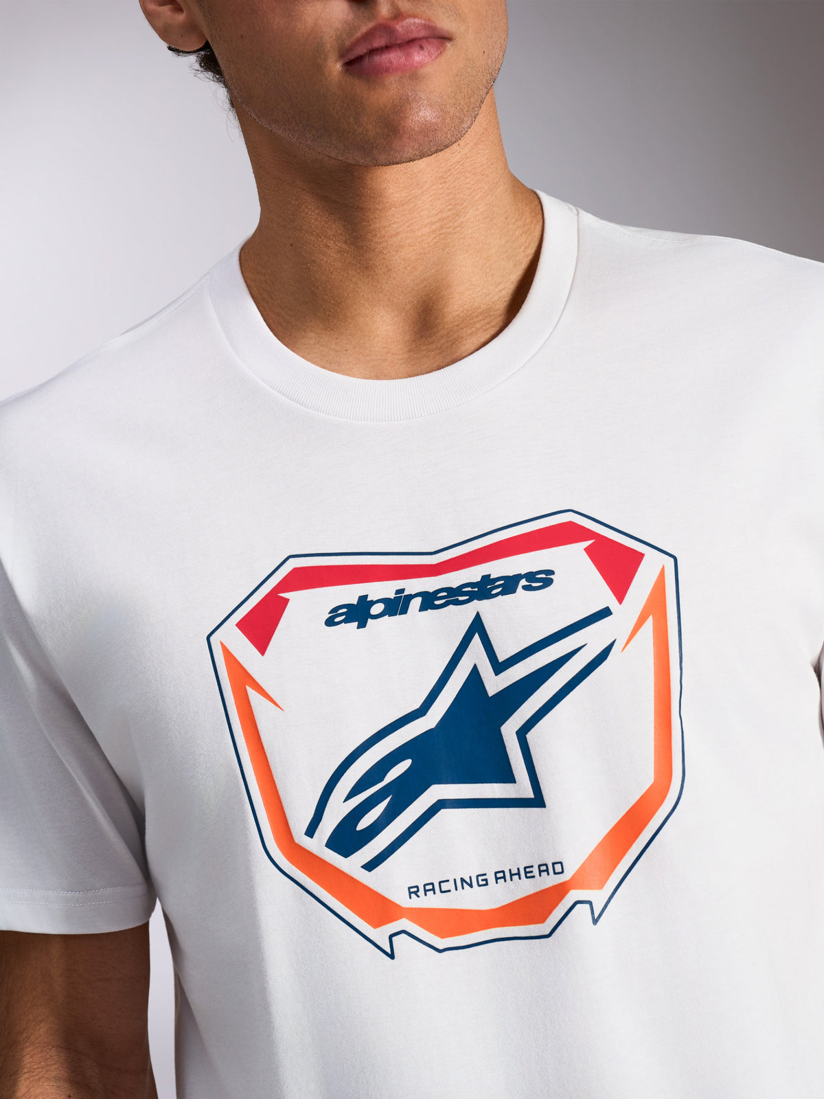 Alpinestars Plate CSF T-shirt, T-shirt met korte mouwen, wit, MX-plaatgrafiek aan de voorzijde met blauw Astars-logo en 'Racing Ahead'-tekst, oranje en rode accenten, casual motorsport-sportkleding