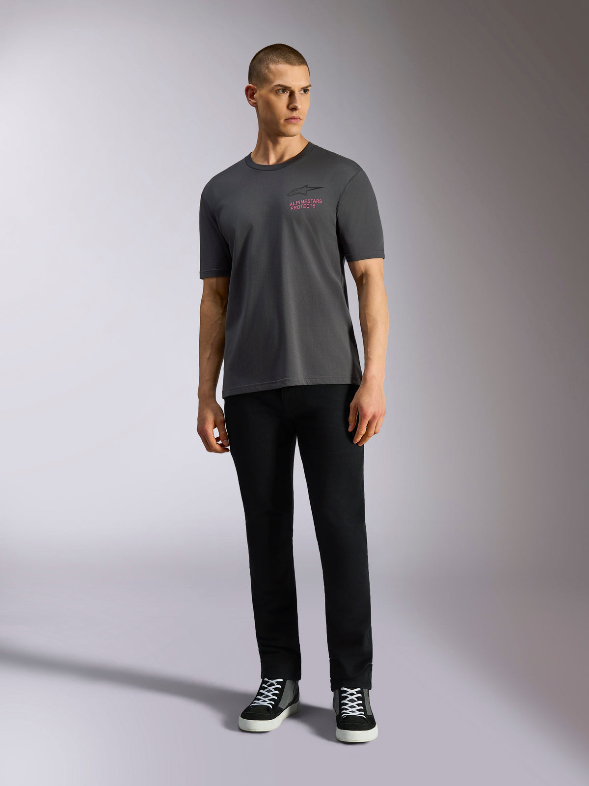 Alpinestars Pop Helmet CSF Tee, Short Sleeve T-Shirt, Charcoal Gray, featuring a pink Alpinestars logo on the chest, worn by a male model with black pants and sneakers, Casual Motorsport Streetwear