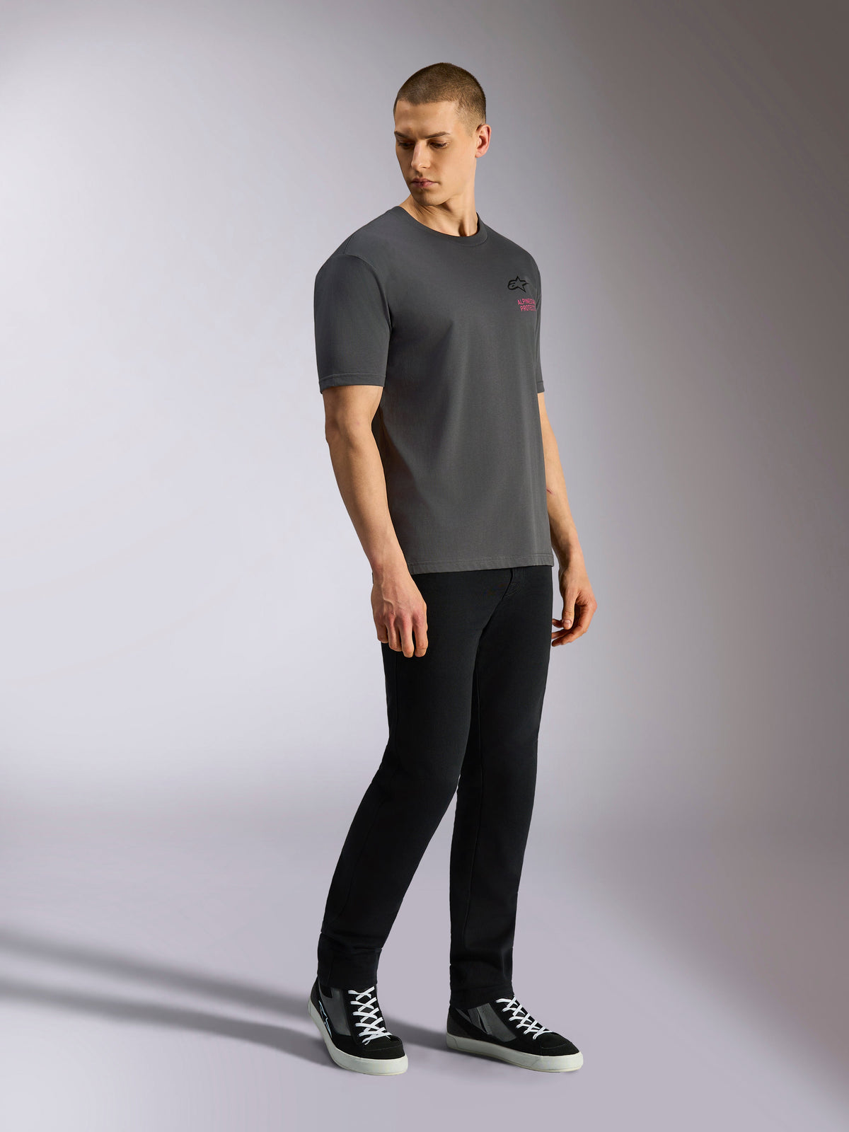 Alpinestars Pop Helmet CSF Tee, Short Sleeve T-Shirt, Charcoal Gray, worn by model with black pants and sneakers, featuring front black Astars logo and pink lettering, casual motorsport streetwear