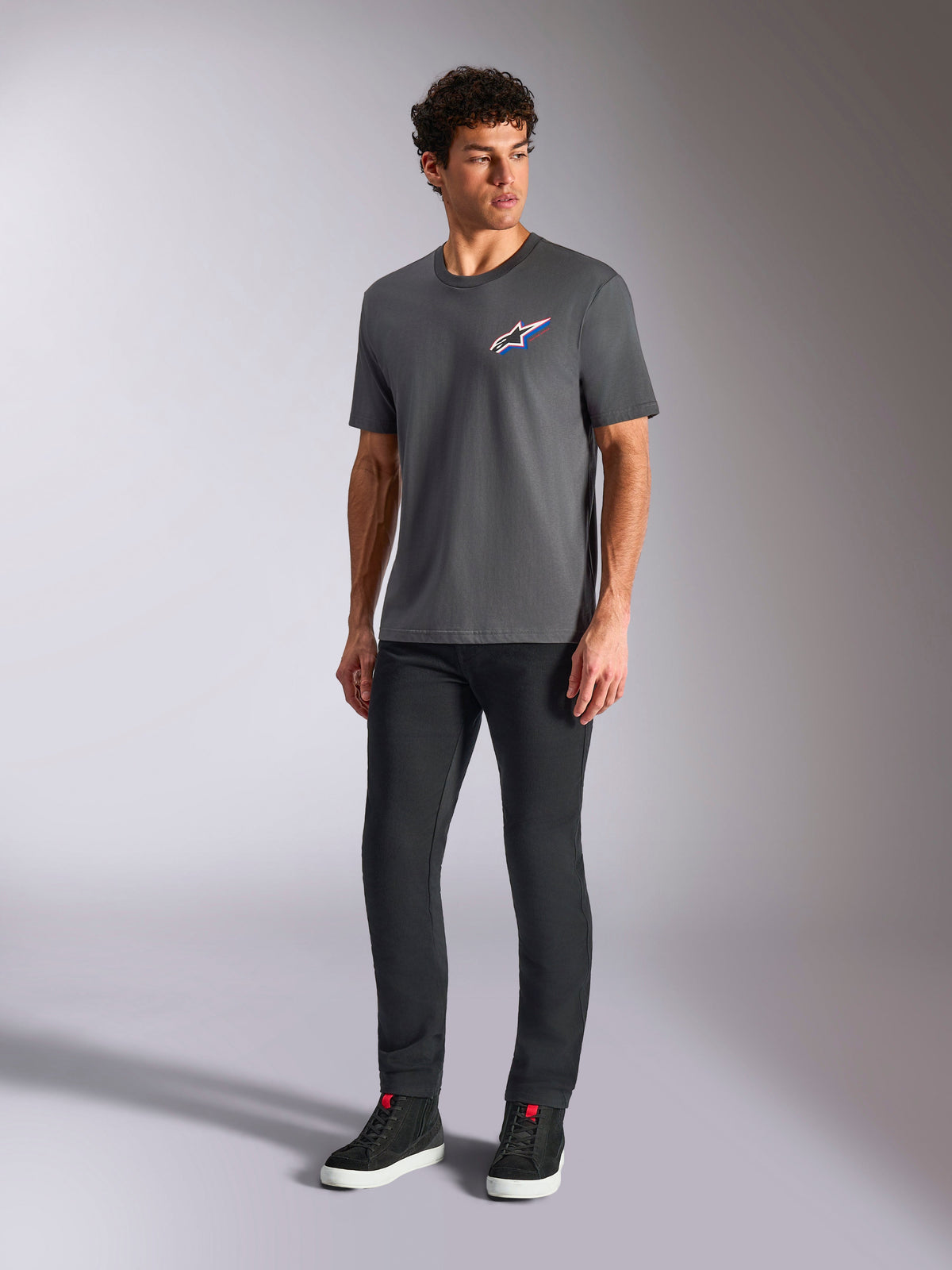 Alpinestars Angler CSF Tee, Short Sleeve T-Shirt, Charcoal, Multi-color Astars Logo on chest, worn with black pants and sneakers, casual motorsport streetwear