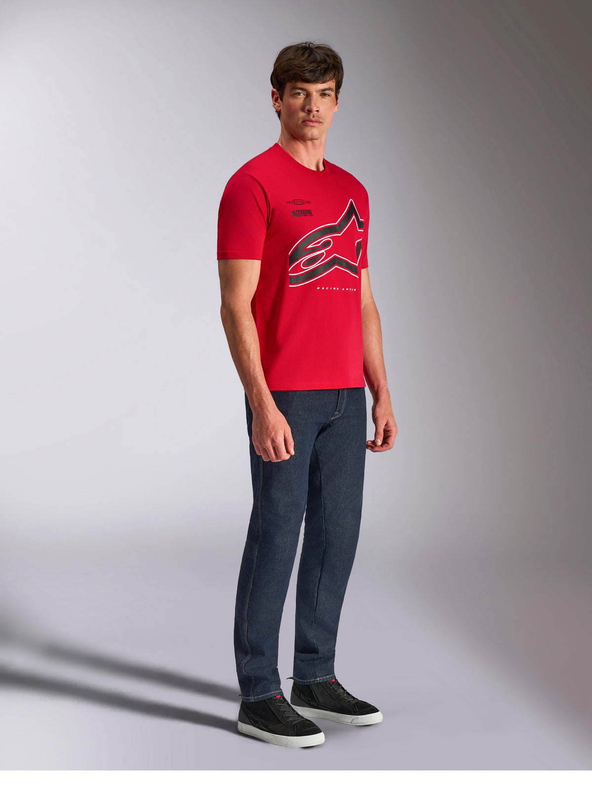 Alpinestars Authority CSF Tee, T-shirt met korte mouwen, rood, groot gecropt Astars-logo met zwarte en witte omtrek, gedragen door model met donkere denim broek en zwarte sneakers, casual op motorsport geïnspireerde streetwear