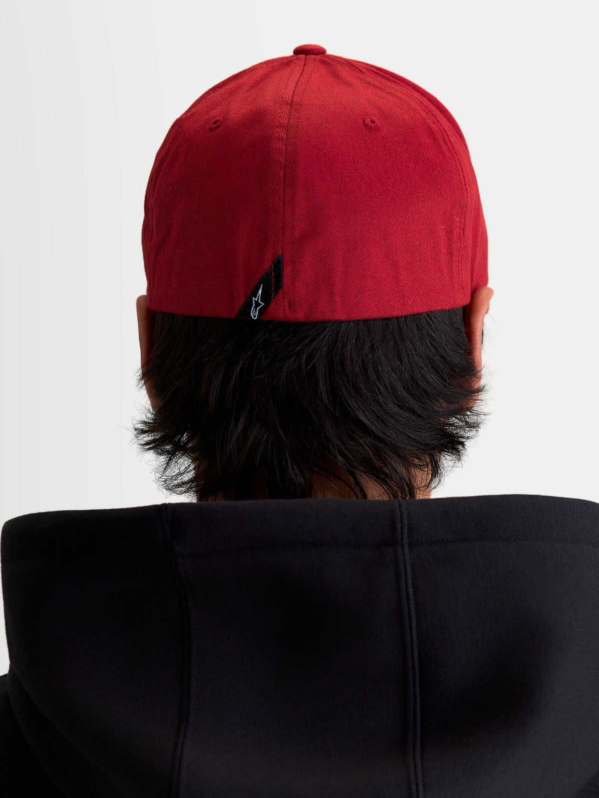 Alpinestars Pivot pet, donkerrode sportswear baseballpet van katoenen keperstof, achteraanzicht op model toont de flexibele achterkant en klein Astars-logolabel op de achterzijde.