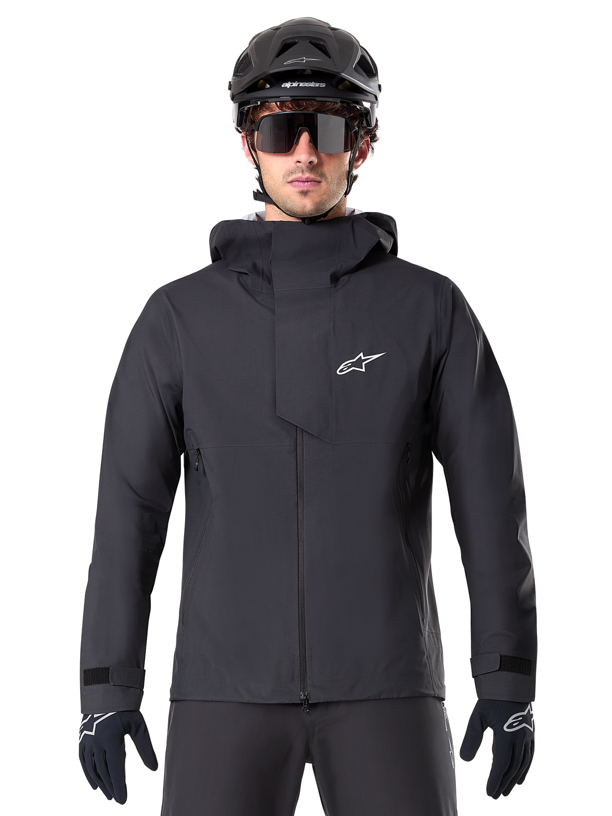 Alpinestars A-Dura Elite Waterproof Jacket, Black, Mountain Bike Jacket, High-collar design with hood, Front zipper with protective chest flap and white logo, Worn with black helmet and cycling gloves, Technical weather protection for trail riding