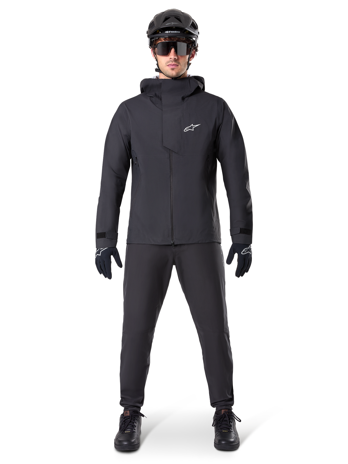 Alpinestars A-Dura Elite Waterproof Jacket, Black, worn with matching cycling pants and gloves, black helmet and sunglasses, featuring a white Astars logo on the chest, high-performance technical design for mountain biking