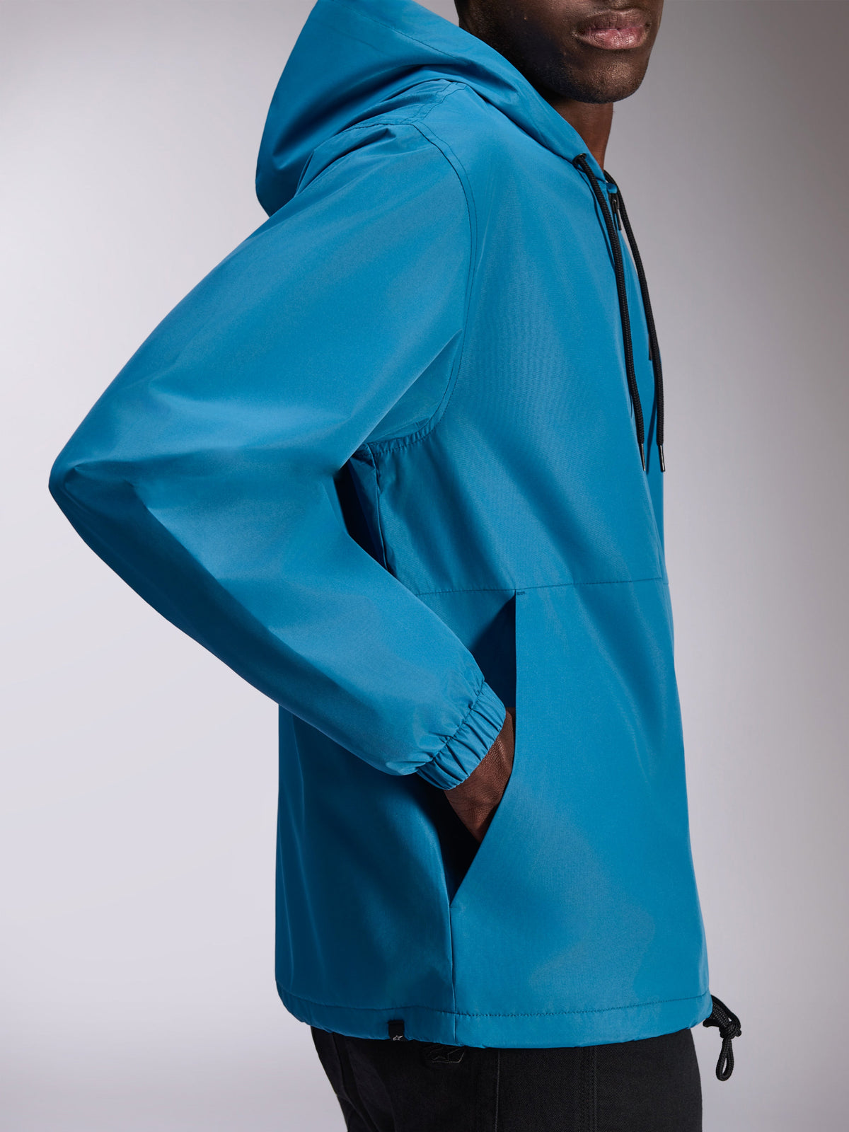 Alpinestars Speeder Chromium Windbreak Jacket, lightweight hooded windbreaker in Blue, side view featuring elastic cuffs and hand pockets, adjustable hood with drawstrings, casual motorsport-inspired design