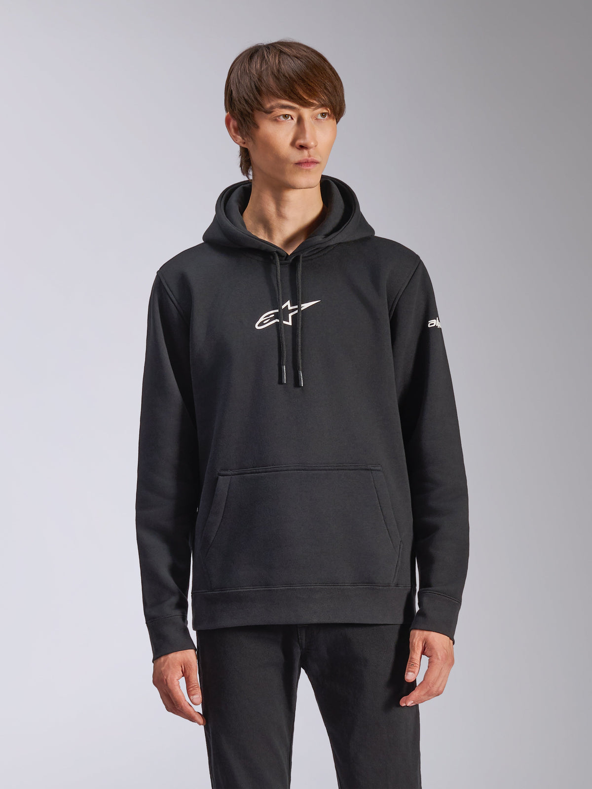 Alpinestars Frontal Hoodie, zwarte pullover fleece hoodie, wit Alpinestars-logo op de borst, wit woordmerk op de mouw, kangoeroezak, casual motorsport streetwear