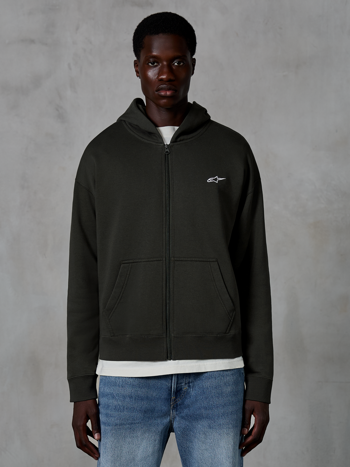Alpinestars Essentials Ageless Zip Hoodie, hoodie met rits, Off Black, met een klein wit sterlogo op de borst, voorzakken en geribbelde boorden, gedragen als casual motorsport-geïnspireerde streetwear