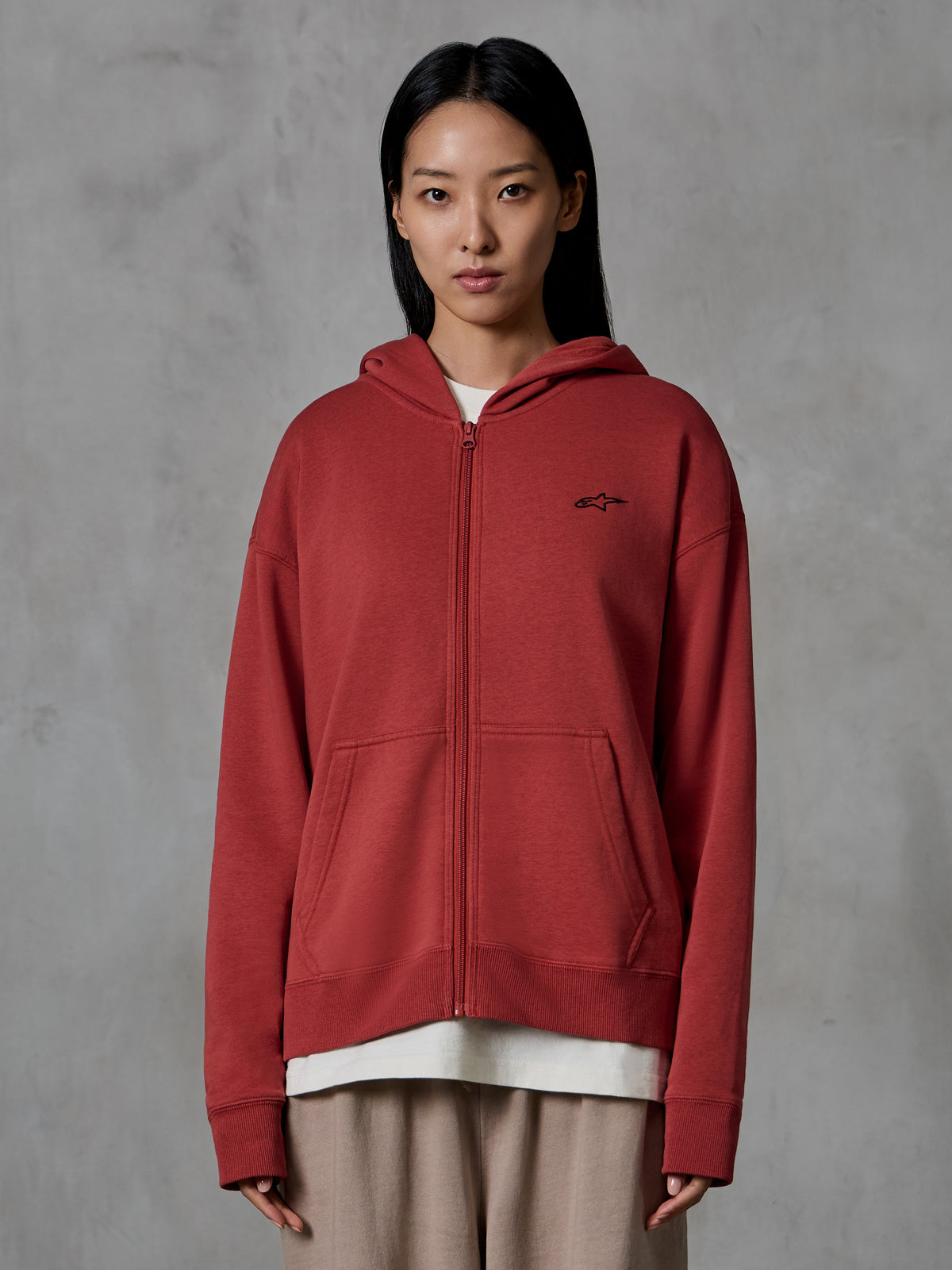 Alpinestars Essentials Ageless Zip Hoodie, Brick red, casual streetwear, worn by a model, full-zip design with hood, small black Alpinestars logo on the chest, relaxed fit compact fleece.