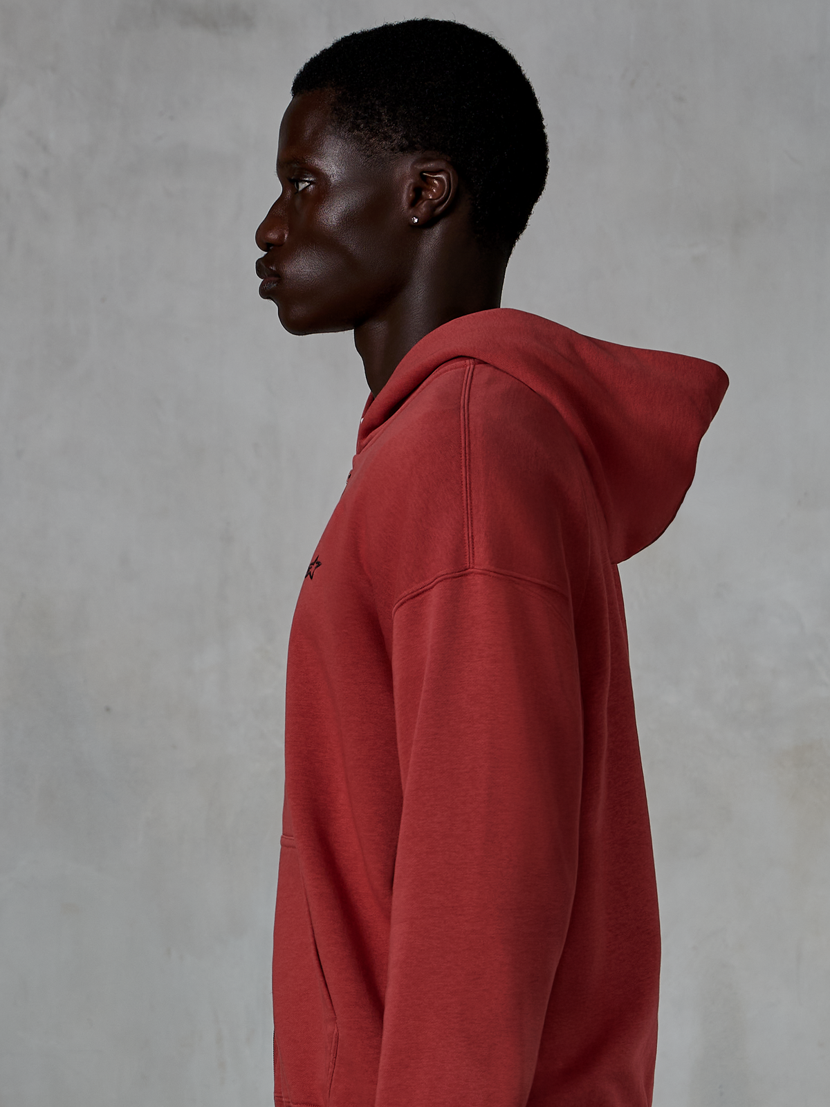 Alpinestars Essentials Ageless Zip Hoodie, Brick red, side profile view of a man wearing a relaxed fit zip-up hoodie, small black star logo on chest, premium stone-washed fleece, casual motorsport-inspired streetwear