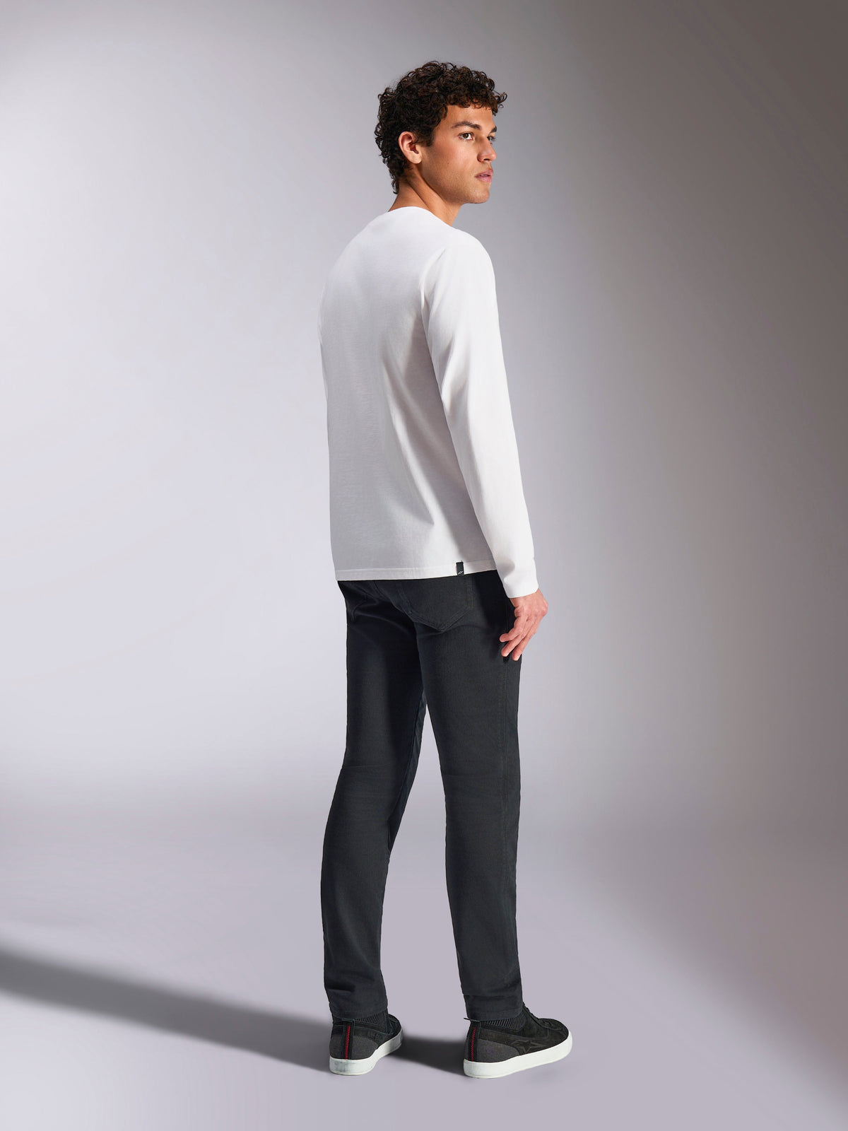 Alpinestars Trackside CSF Tee, T-shirt met lange mouwen, wit, mannelijk model van achteren gezien met zwarte broek, casual streetwear geïnspireerd op de motorsport