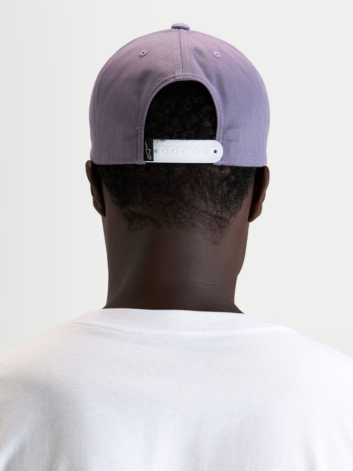 Alpinestars Ageless Snapback Pet, paarse sportswear-pet met verstelbare witte snapbacksluiting en gestructureerde kroon, gedragen vanaf de achterkant