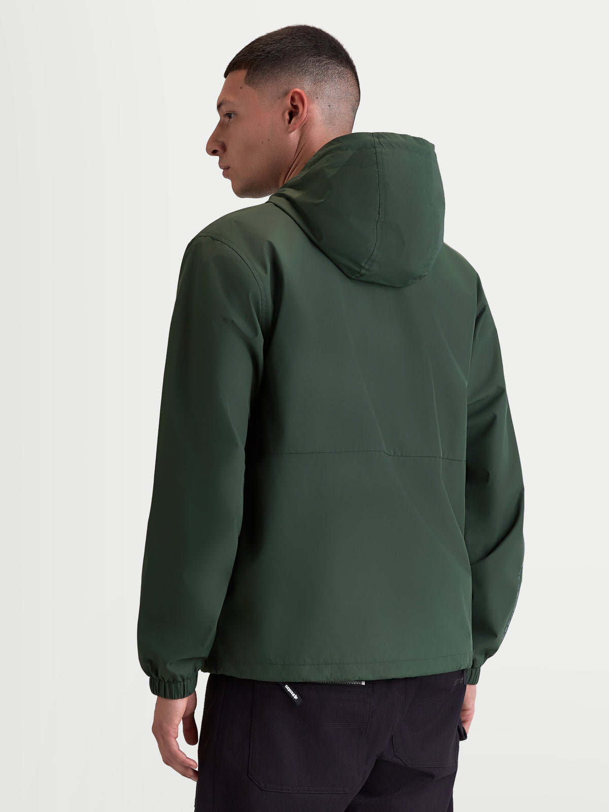 Alpinestars Speeder Resolve Windbreaker Jas, lichtgewicht sportswear met capuchon voor stedelijk gebruik, groen, winddicht 100% polyester met meshvoering, achteraanzicht op model met focus op het strakke rugontwerp en elastische manchetten.