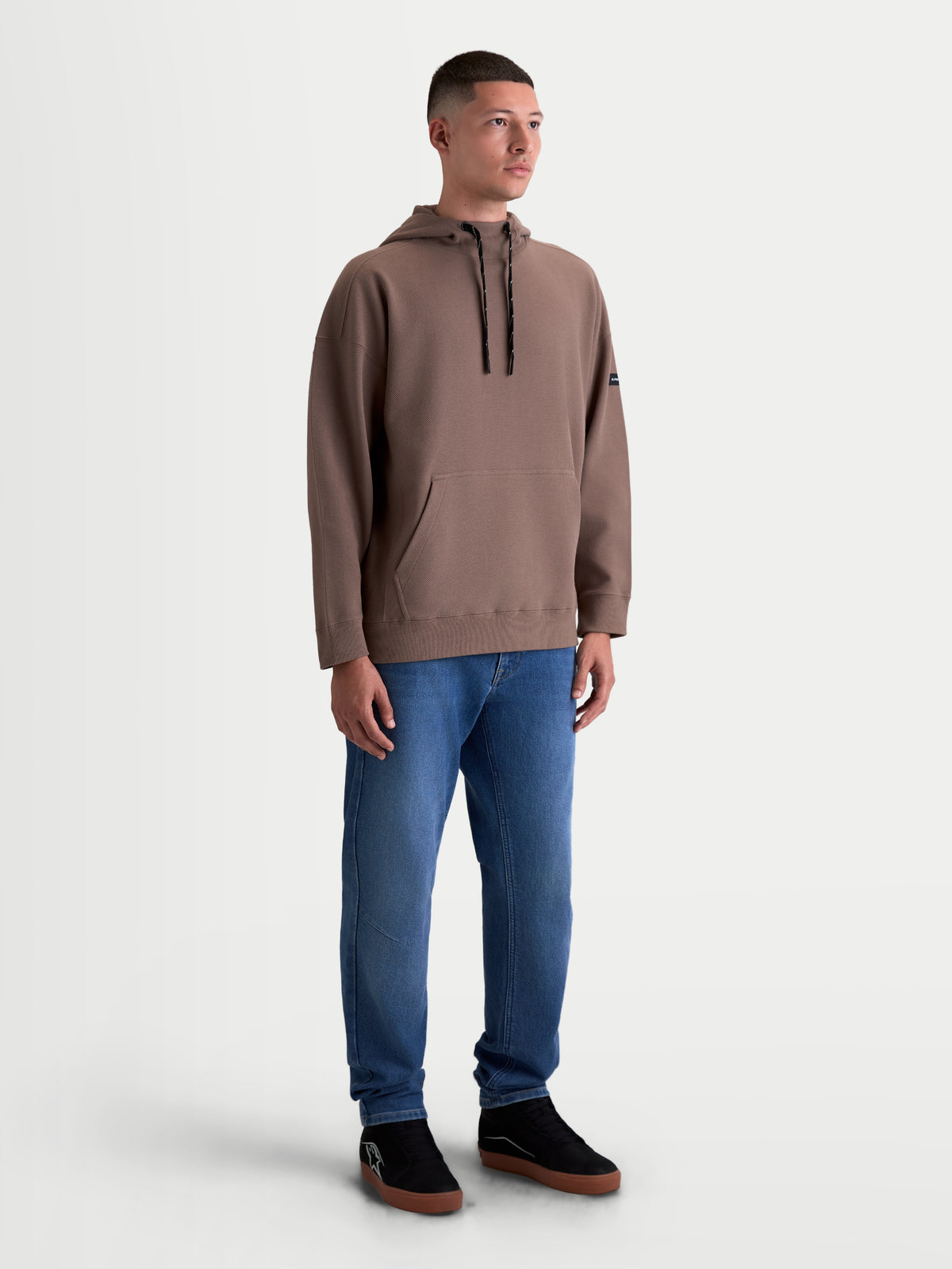 Alpinestars Camino Textured Oversized hoodie, heren casual sportswear, bruin, met gestructureerde twill-fleece, een hoge kraag en een kangoeroezak, relaxte oversized pasvorm, getoond op model.