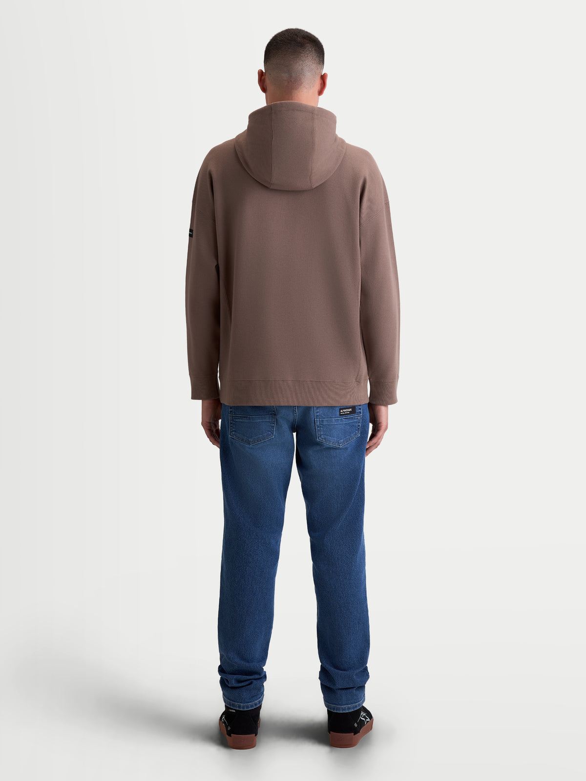 Alpinestars Camino Textured Oversized hoodie, herensportswear casual pullover, bruin taupe, achteraanzicht op model, gestructureerde knit twill fleece constructie met ribgebreide boorden en zoom.