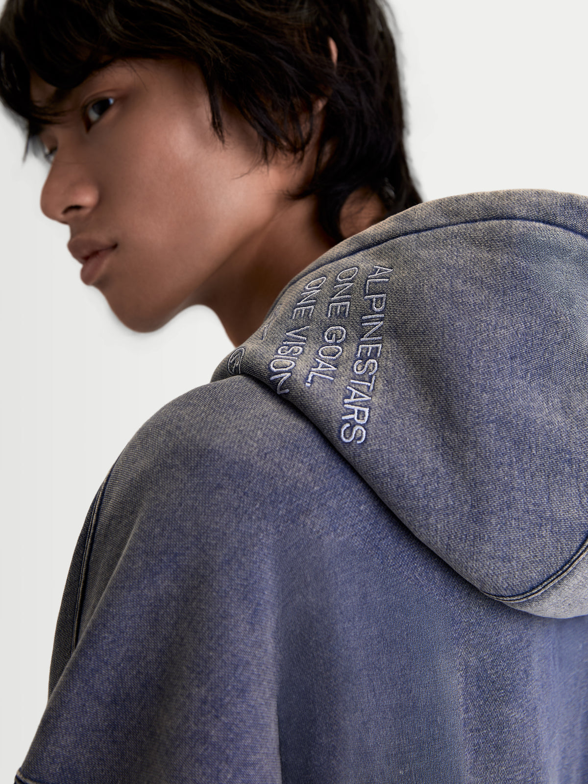 Alpinestars Infinite Washed Oversized hoodie, sportswearpullover voor heren en dames, blauw, close-up van de capuchon met het 'ONE GOAL. ONE VISION.' borduursel en de getextureerde snow-wash afwerking op het fleece materiaal.