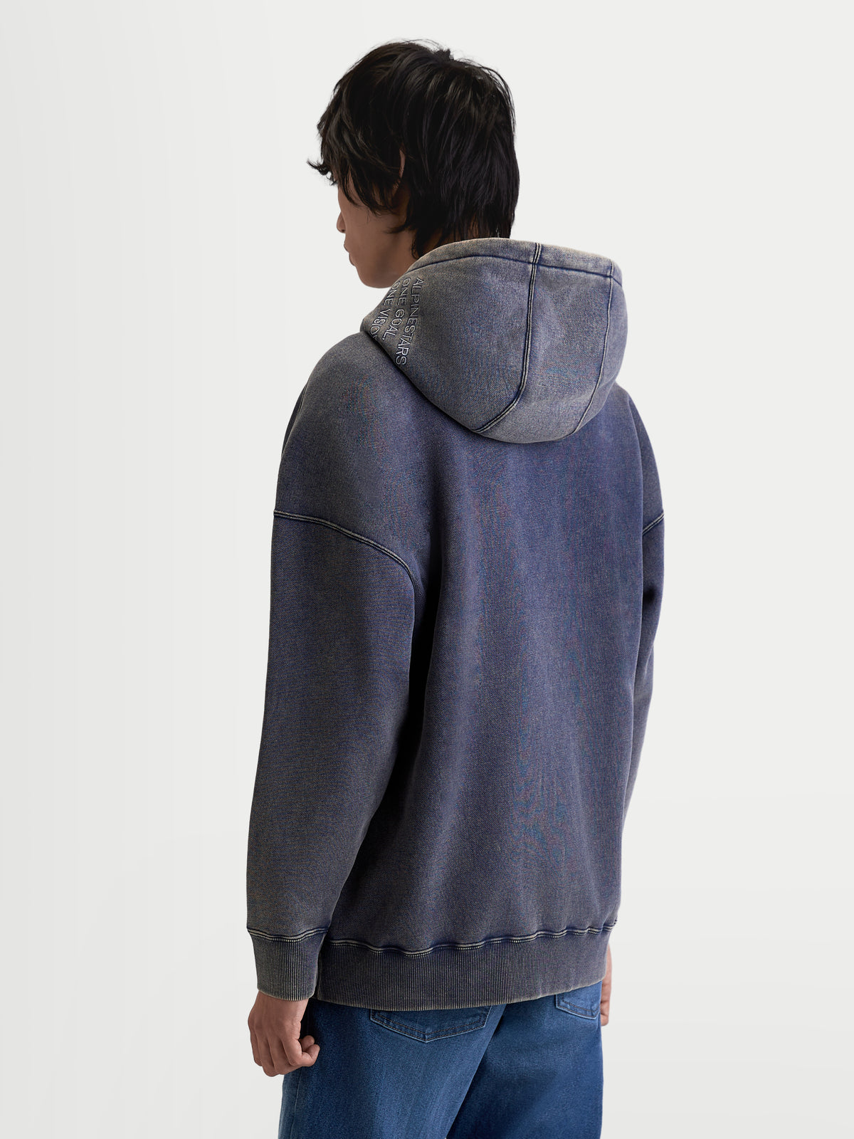 Alpinestars Infinite Washed Oversized Hoodie, casual sportswear-hoodie, unisex, gewassen marineblauw, snow-wash-afwerking, premium katoenmix fleece, voorzien van Alpinestars wordmark en One Goal One Vision borduring op de capuchon, ontspannen pasvorm, achteraanzicht op model.