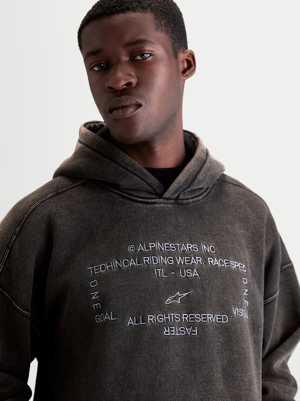 Alpinestars Infinite gewassen oversized hoodie, heren sportswear hoodie, gewassen zwart met snow-wash afwerking, geborduurde Alpinestars logo's en 'One Goal One Vision' tekst, casual fleece kleding.