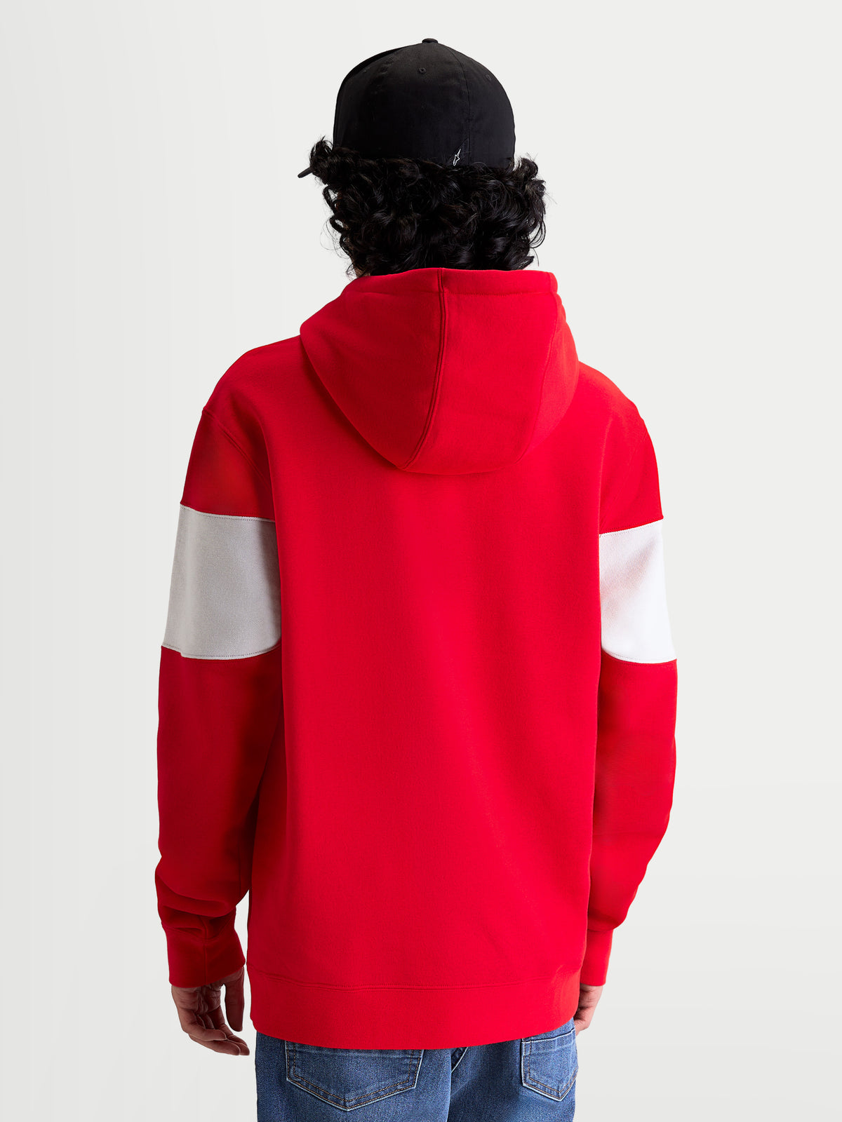 Alpinestars Cubic Hoodie, sportswear pullover fleece, rood en wit, achteraanzicht op model met zwarte pet, voorzien van kleurgeblokte mouwen, een gevoerde capuchon en geribde manchetten voor een motorsport-geïnspireerde look.