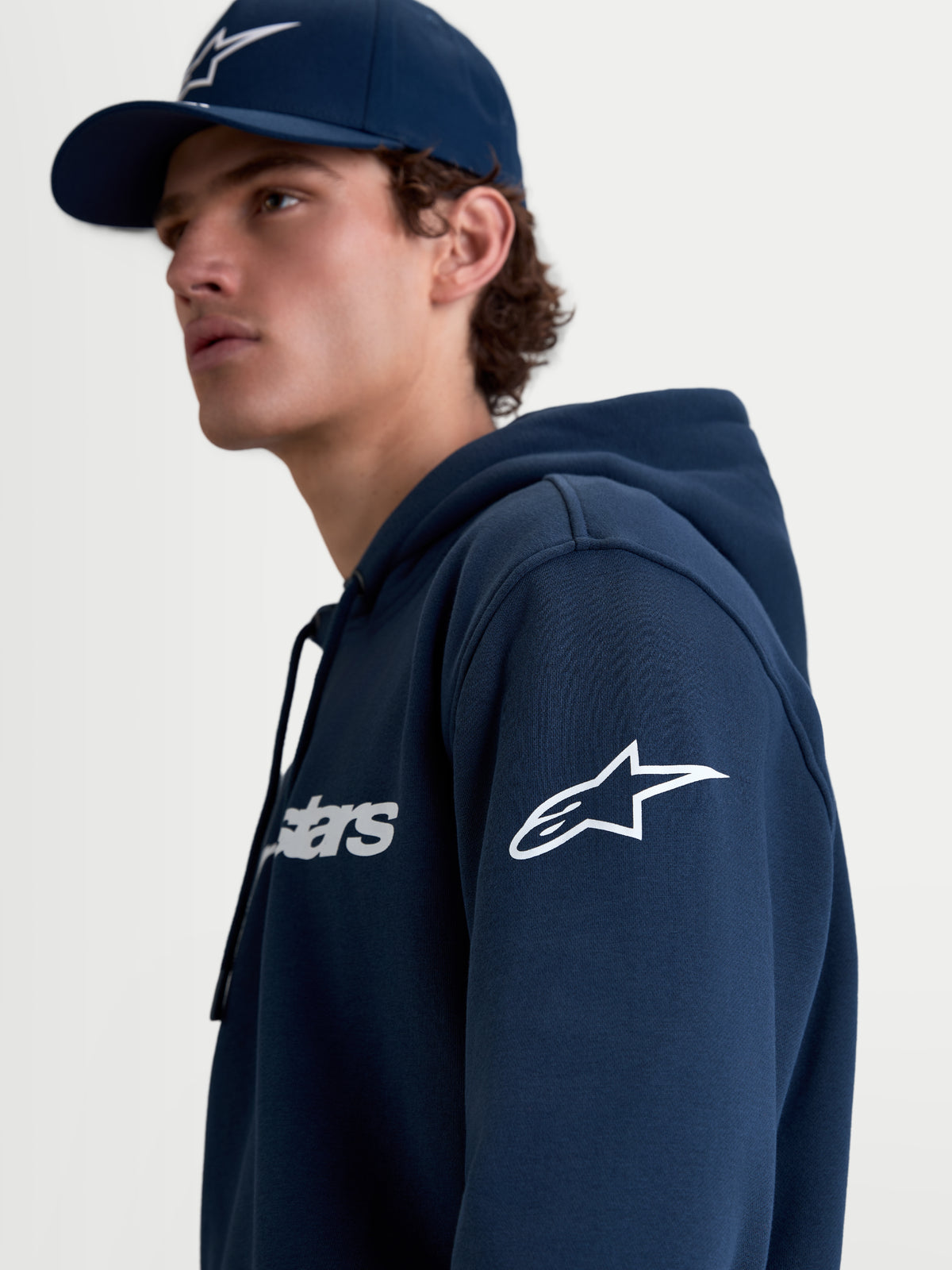Alpinestars Race Wordmark hoodie, heren sportswear fleece pullover, marineblauw en wit, wit Ageless-logo op de mouw en Race Wordmark op de borst, lifestyle-weergave op model.