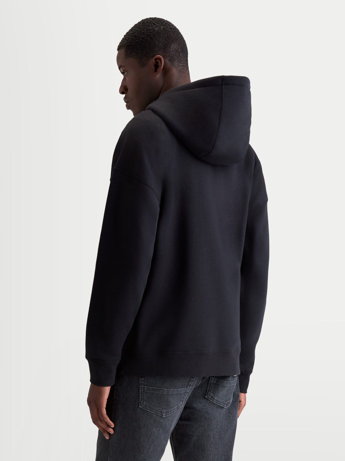 Alpinestars Entity oversized hoodie, sportswear fleece met ritssluiting, zwart, oversized pasvorm, achteraanzicht op model, zelfgevoerde capuchon en ribboorden, premium katoen en gerecycled polyester mix.