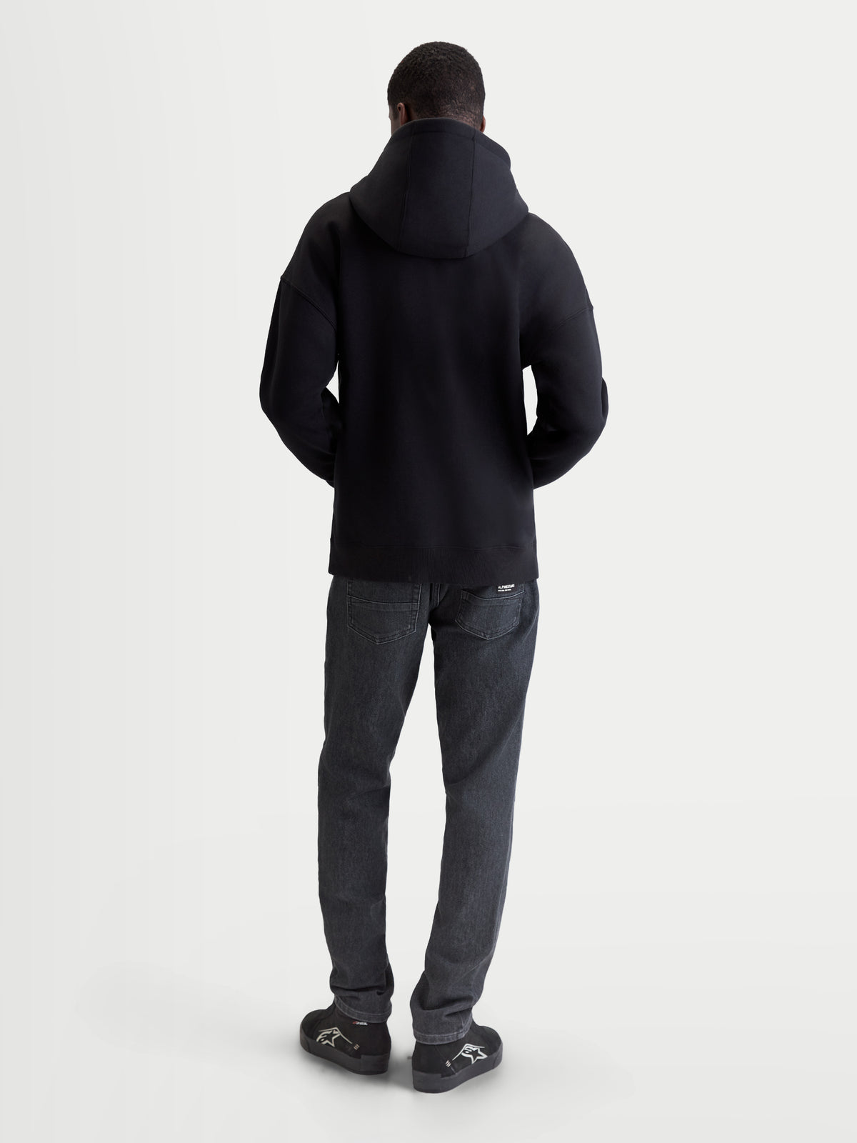 Alpinestars Entity oversized hoodie, heren-sportswear zip-fleece, zwart, achteraanzicht op model, relaxte oversized pasvorm, katoen en gerecycled polyester, casual motorsportkleding