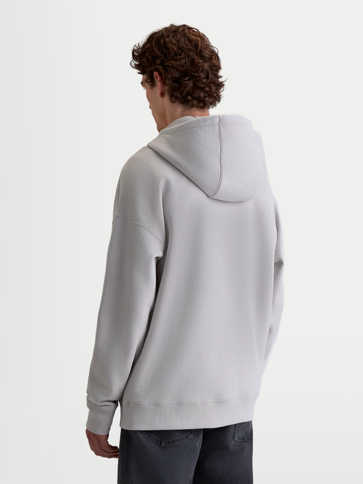 Alpinestars Entity Oversized Hoodie, casual sportkleding fleece voor heren en dames, achteraanzicht op model, cement grijs, met een relaxte oversized pasvorm, verlaagde schouders, zelfgevoerde capuchon en geribbelde boorden.