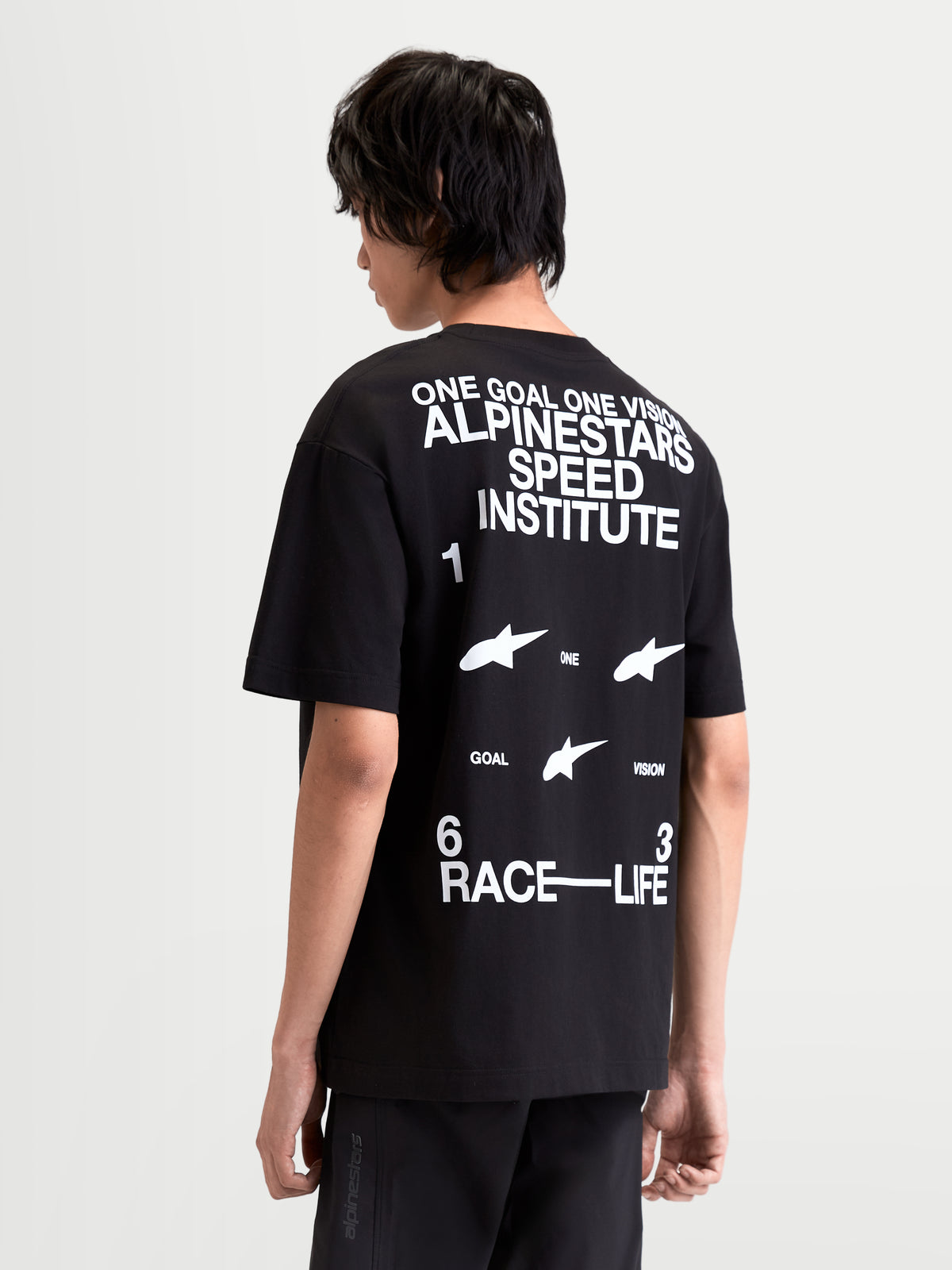 Alpinestars Institute Oversized CSF T-shirt, sportswear T-shirt met korte mouwen, zwart en wit, achteraanzicht op model met witte 'One Goal One Vision Alpinestars Speed Institute' en 'Race-Life' graphics op de rug, relaxed oversized pasvorm, 60/40 katoen-polyestermix.