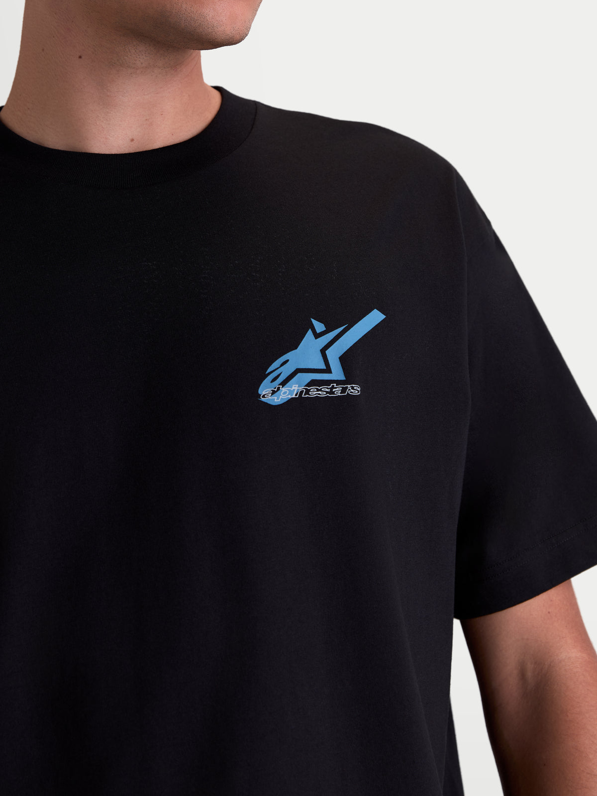 Alpinestars Ghost Oversized CSF T-shirt, casual sportswear T-shirt met korte mouwen, zwart met blauw en wit Astars-logo op de borst, katoen-polyestermix, close-up op model.