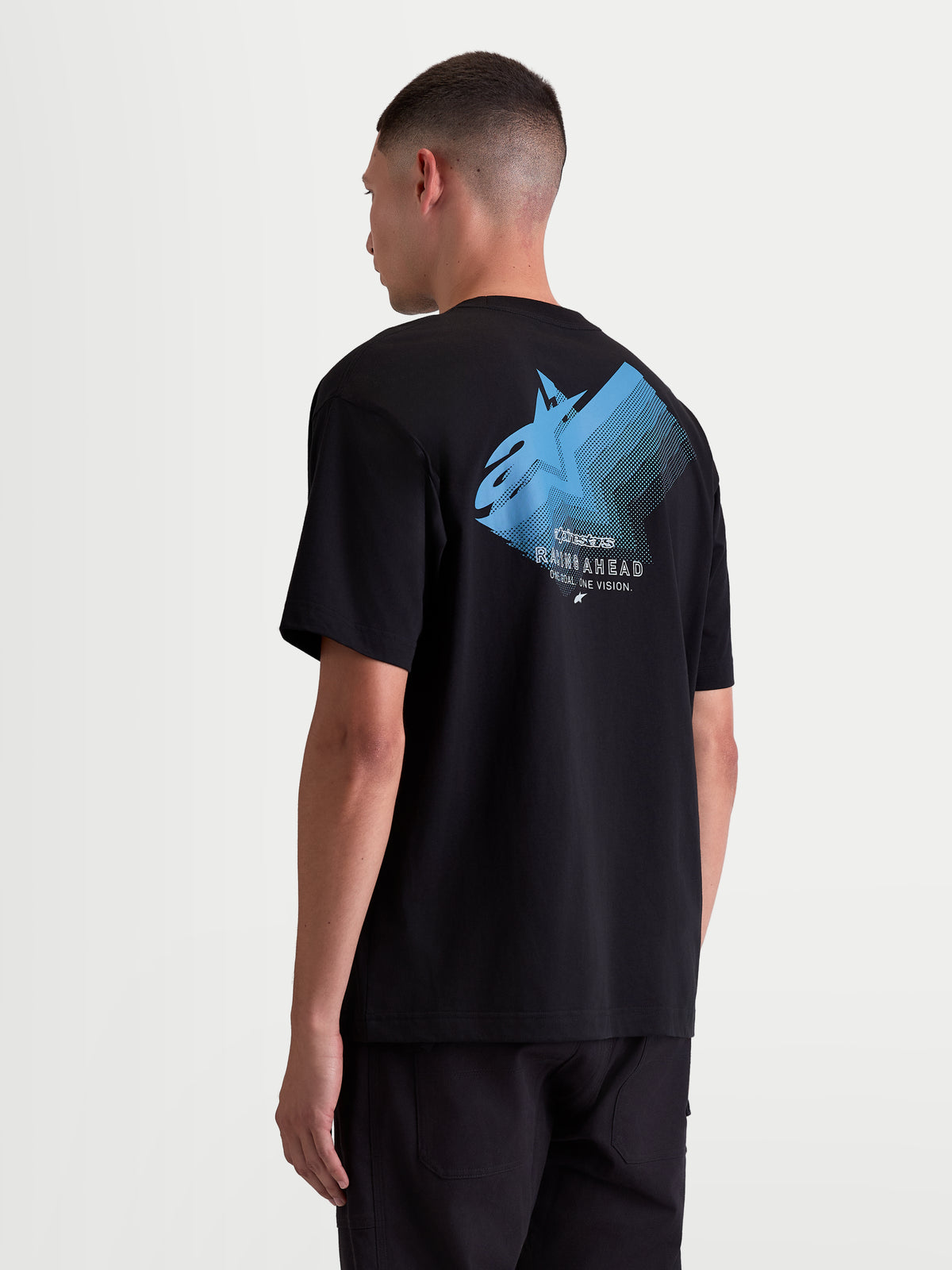 Alpinestars Ghost Oversized CSF t-shirt met korte mouwen, zwart en blauw, achteraanzicht op model met groot Astars fade-logo en 'Racing Ahead' tekst, zachte katoen-polyestermix, casual sportswear.