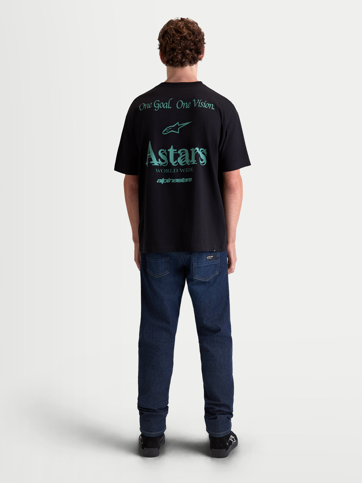 Alpinestars Post Oversized CSF t-shirt, sportswear-t-shirt met korte mouwen, zwart met petrolblauwe graphics op de rug, One Goal. One Vision. en Astars World Wide-logo, oversized pasvorm, zachte katoenmix, gezien van de achterzijde.