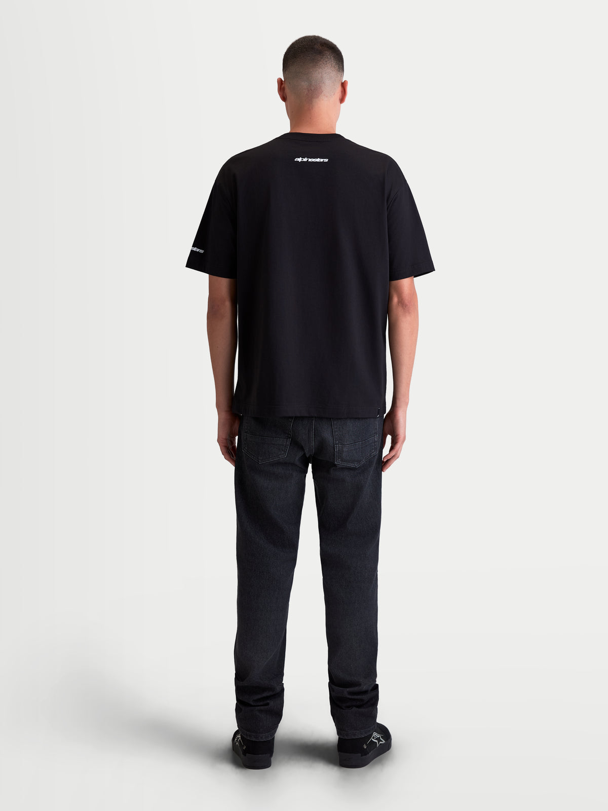 Alpinestars Mandate Oversized CSF T-shirt, casual sportswear t-shirt met korte mouwen, zwart, achteraanzicht op model met witte puff-print logo's op de nek en mouw, ontspannen oversized pasvorm, 60/40 katoen-polymix.