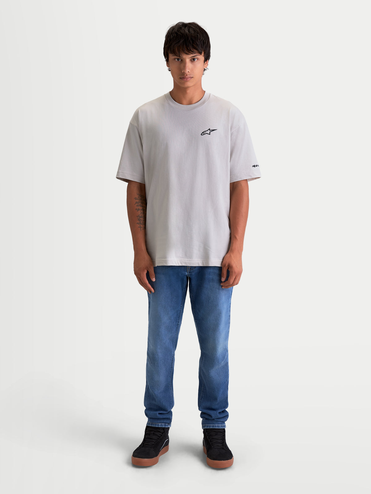 Alpinestars Mandate Oversized CSF t-shirt, heren-t-shirt met korte mouwen, cement grijs, oversized pasvorm, zwart puff-print Astars-logo op de borst en mouwgraphics, katoen-polyestermix, casual lifestyle sportswear, getoond op model.