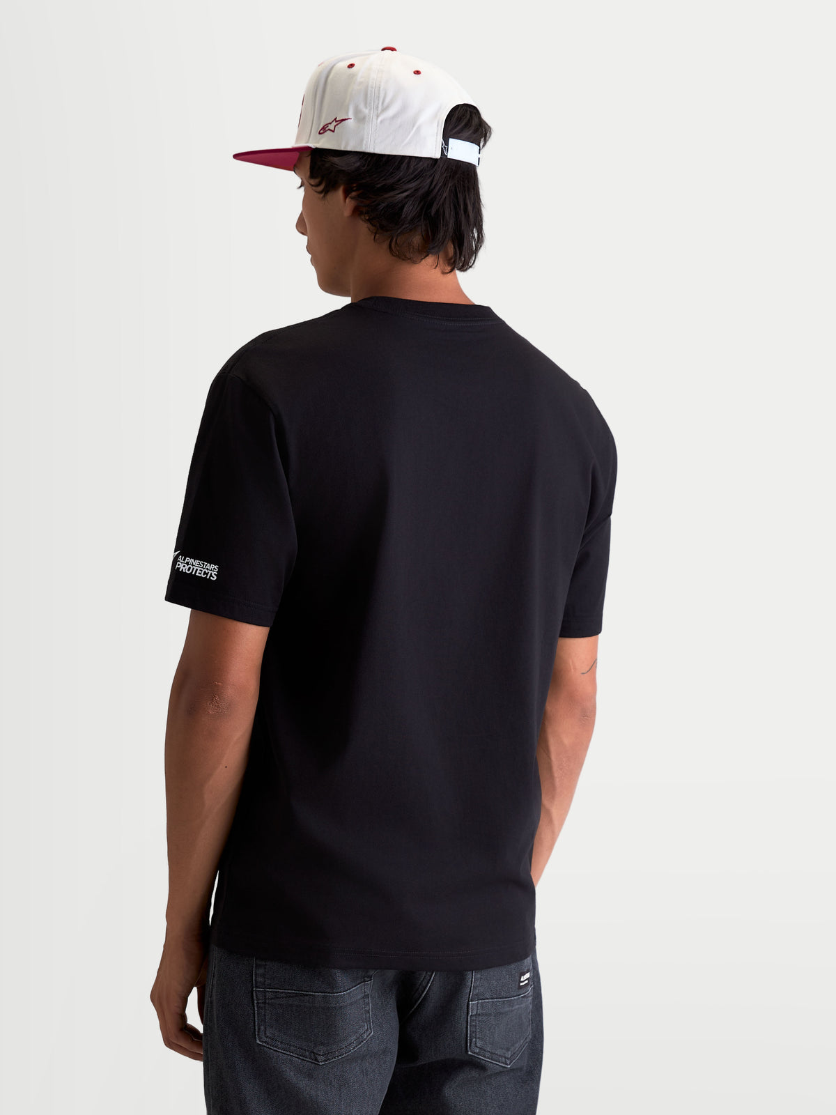 Alpinestars P1 CSF T-shirt, motorsport t-shirt met korte mouwen, unisex, zwart, zachte katoen-polyestermix, achteraanzicht op model met Alpinestars Protects-logo op de mouw, casual sportswear.