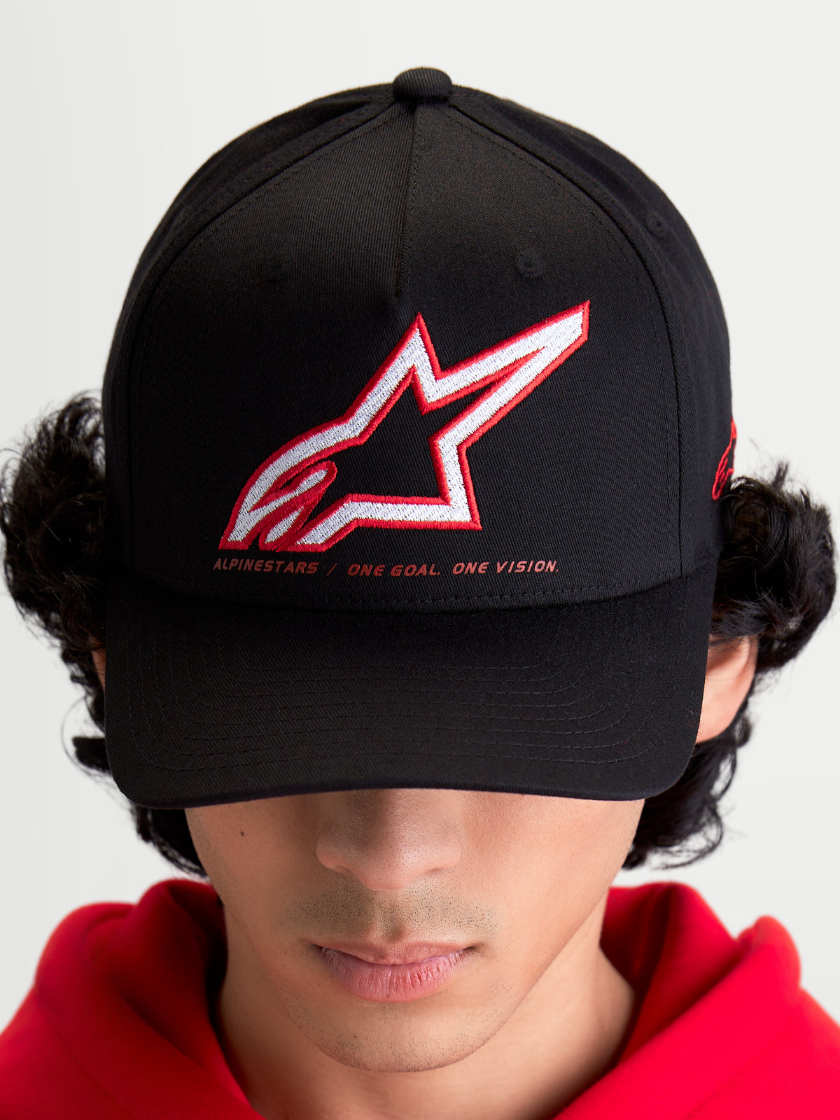 Alpinestars Lineout pet, sportswear baseballpet voor heren en dames, zwart met rood en wit geborduurd Astars-logo en One Goal One Vision-slogan, gebogen klep, gestructureerde kroon, textielconstructie.