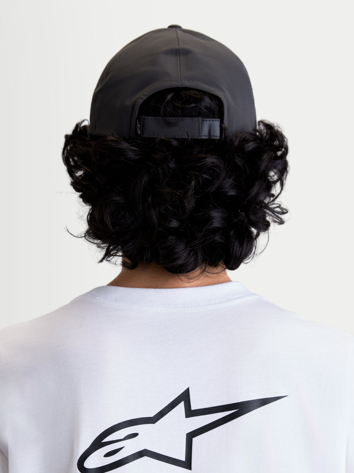 Alpinestars Algo Perf verstelbare pet, grijze sportswearpet van technische stof met een verstelbare snapbacksluiting, achteraanzicht op model toont de pasvorm en gestructureerde kroon.